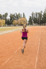 Obraz premium Sporty woman running on stadium track