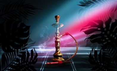 Smoking hookah on a dark abstract background, neon light. Silhouettes of tropical palm leaves in the foreground.