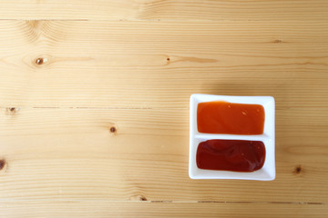 Ketchup and chilli sauce on compartment bowl on wood table Left copy space