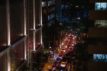 cidade de noite rua com transito de carros, prédios e árvores na vila olimpia