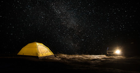 Camping for a starry night. The tent glows under the night sky full of stars. Milky Way. leisure tourists. for friends