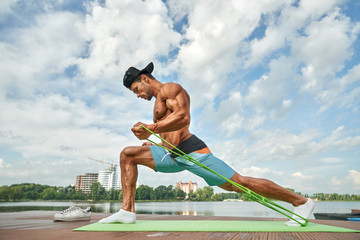 Man doing lunge exercises for legs with expander.