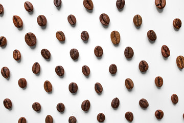 different varieties of coffee brown beans on a white isolated blurred background laid out in a staggered manner