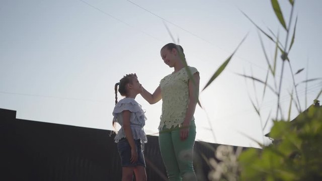 Mom and her little daughter standing on the street in the summer evening and talking heart to heart with love. Relationship mom and daughter. Real happy family.