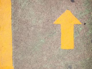 Yellow arrow painting on gray concrete background