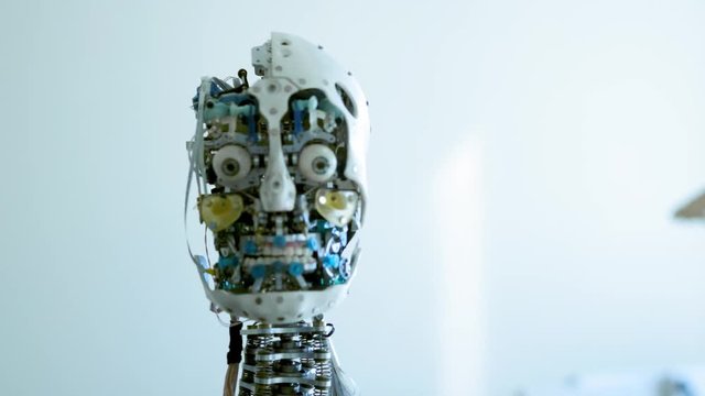 Futuristic humanoid female robot is idle. Concept of future. The head of a humanoid android humanoid robot. The robot turns his head, blinks his eyes. Android skull