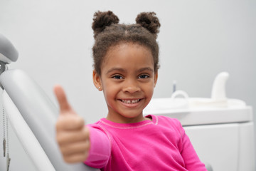 Small african girl showing thumb up in dentist office