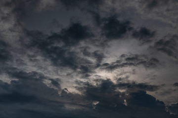 Fototapeta premium Beautiful evening skyscape. Sun's rays shine through hole in black clouds after rain, natural background.