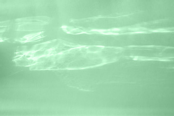 Trendy mint colored abstract background with light and shadows caustic effect. Light passes through a glass.