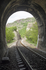 Fototapeta na wymiar View from inside railroad tunnel outside and rails in the mountain in Bulgaria