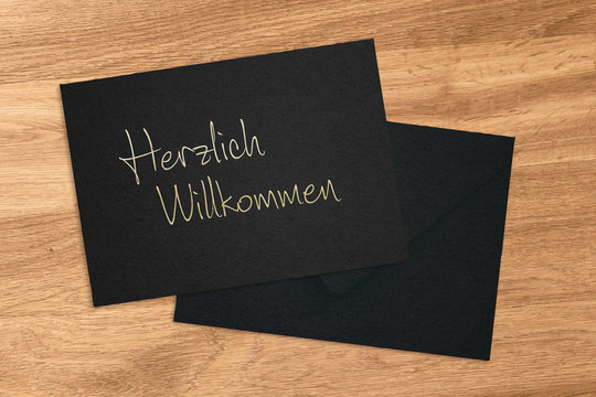 Goldener Schriftzug "Herzlich Willkommen" auf schwarzem Papier-Untergrund
