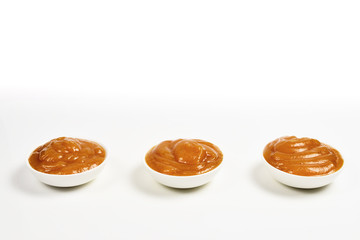 Orange sauce in white plate on white background.