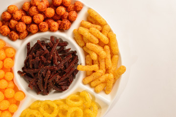 Mix of snacks on a white plate isolated on white.
