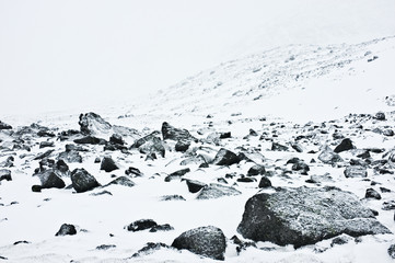 View on khibini mountain, Kola Peninsula, Russia. Strong wind, snow dust and black boulders around. Extreme conditions.