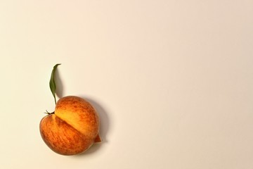 Ripe yellow-red peach with green leaf. With half longitudinal division in half. On a light...