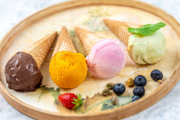 Chocolate, mango,lemon and candyfloss,Ice cream in the cone i a old tray with fresh berry, on white