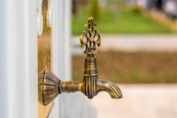 Side view of ornamental water fountain spigot in a public park