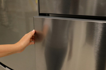 Abstract hand of a young woman is opening a refrigerator door