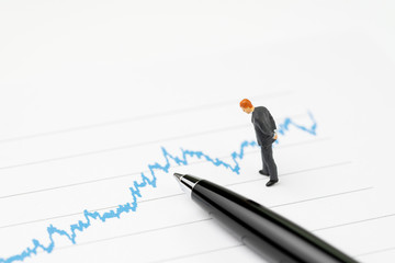 Financial performance graph analysis concept, miniature professional businessmen standing and...