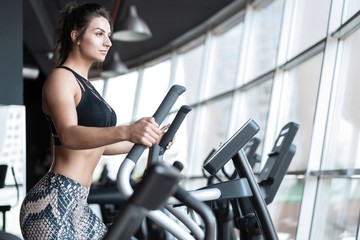 Fototapeta na wymiar Beautiful gym woman exercising on a cardio machine smiling.