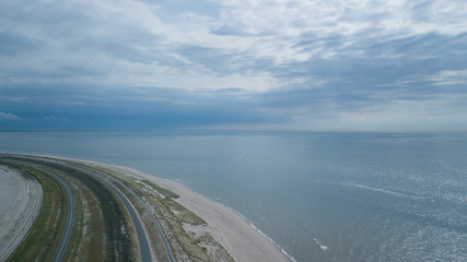 Dike to the North Sea. Sunny weather with clouds. Aerial view from Maasvlakte.
