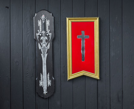 cross of templar and sword on black wooden background