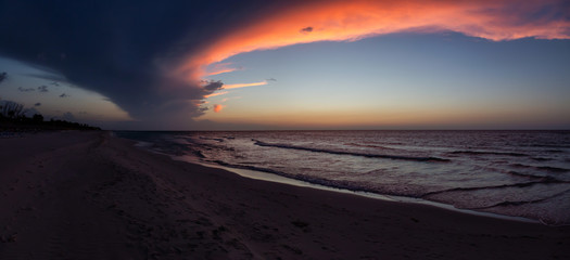 Fototapeta na wymiar Beautiful panoramic view of the sandy beach during a dramatic cloudy sunset. Taken in Varadero, Cuba.