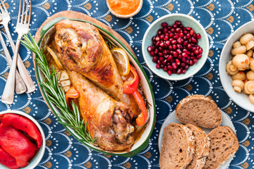 Festive dish for Thanksgiving, roasted turkey legs with vegetables on a table with snacks.