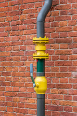 pipe with a valve on the background of a brick wall