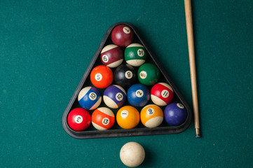 Old billiard balls and stick on a green table. billiard balls isolated on a green background.
