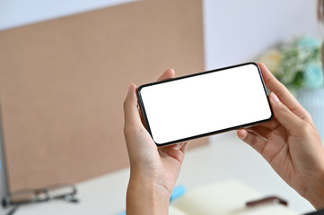 Cropped shot woman using mockup smartphone on office desk.