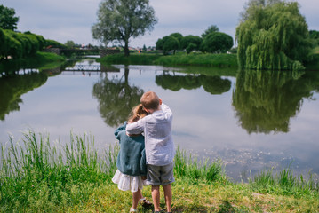 Back view of little children looking at lake on summer day