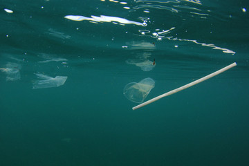 Plastic pollution in ocean. Plastic bottles, bags, cups and straws pollute sea 