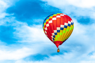 Multicolor balloon flies in the blue cloudy sky. Concept - summer tourism, sport, travel, adventure