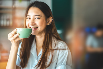 Asian woman in a cafe drinking coffee .Portrait of Asian woman smiling in coffee shop cafe vintage colour tone.