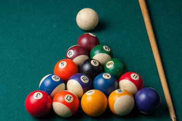 Old billiard balls and stick on a green table. billiard balls isolated on a green background.