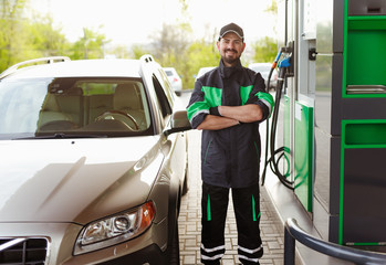 Confident filling station worker near car