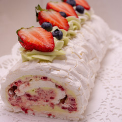 Meringue roll decorated with blueberries and strawberries.