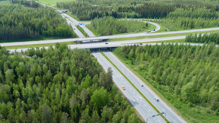 Aerial view of highway and overpass with green forest on a summer day. 