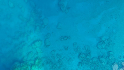 Fototapeta na wymiar Blue sea water texture aerial drone view. Blue lagoon water surface. Rocks underwater.
