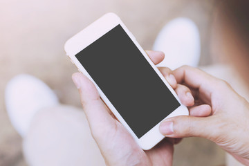 Close up of a young man hand holding using mobile smart phone with screen empty cell phone. he sitting chair in public park outdoor. Top view with copy space.