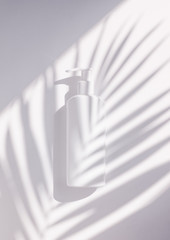 Creative minimalistic shot cosmetic packaging plastic mock up with shadow palm leaves. Mock-up for branding and label.