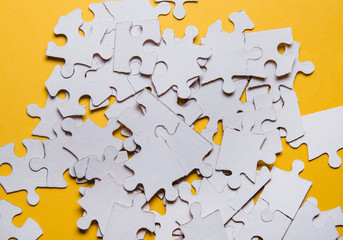 Fototapeta premium Divided pieces of the puzzle on a yellow background. The concept of finding the right solutions in teamwork