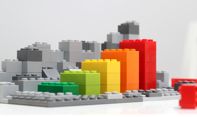 Progress chart made of brick toys. Isometric composition of colourful toys on white table.
