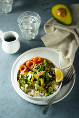 Healthy rice bowl with avocado, salmon and cashew nuts