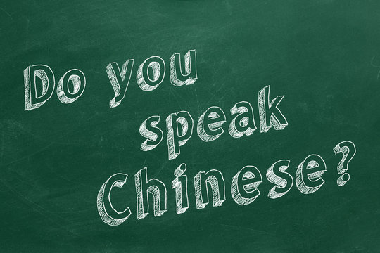 Hand drawing "Do you speak Chinese?" on green chalkboard