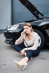 upset businesswoman talking on smartphone near broken auto, car insurance concept