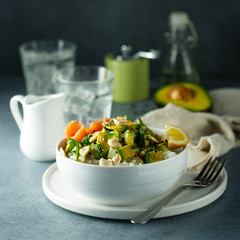Healthy rice bowl with avocado, salmon and cashew nuts
