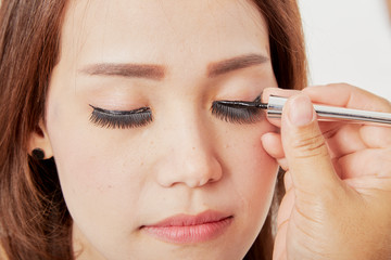 Makeup artist glues eyelashes on client