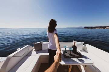 woman holding man's hand on luxury yacht